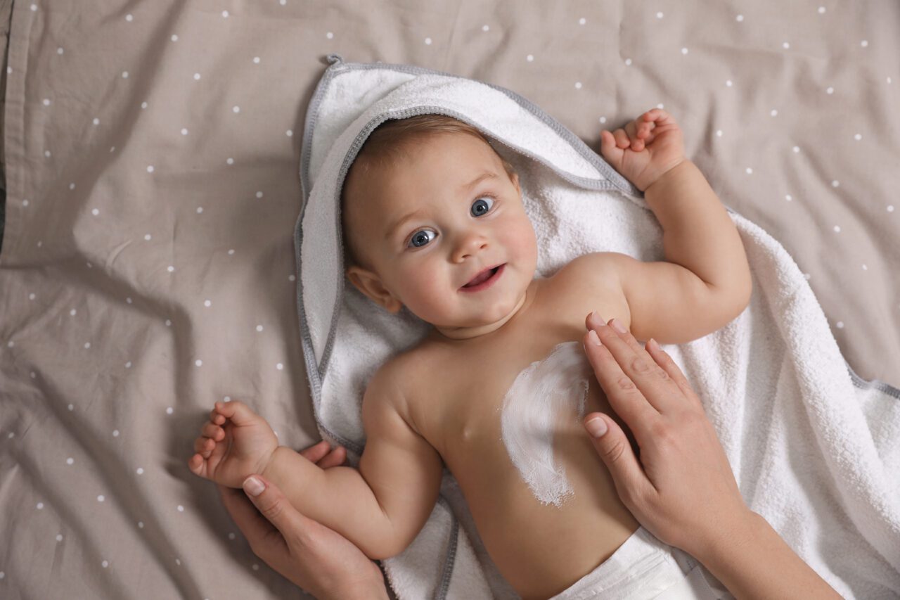 moisturizing cream onto her little baby's skin
